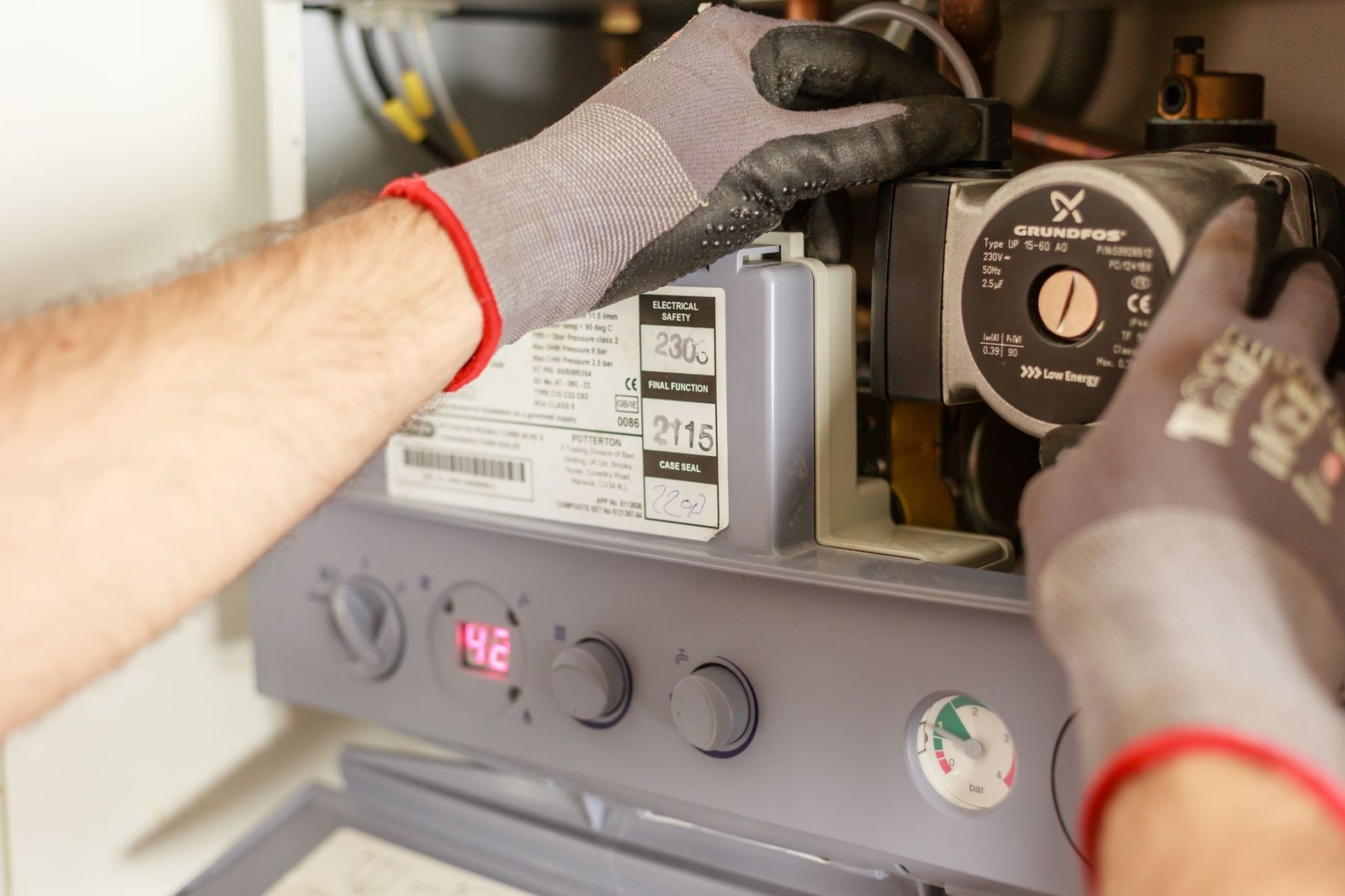 Technician adjusting controls and gauges on a residential boiler system