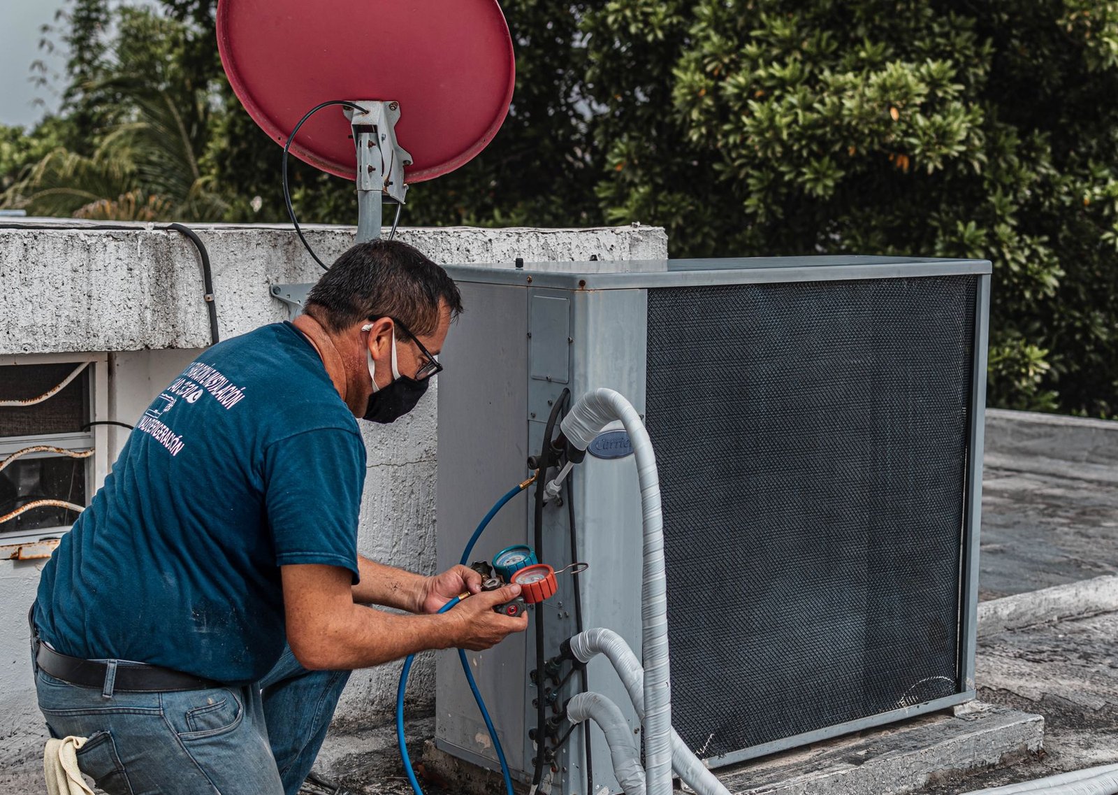 Technician using service gauges to check an outdoor air conditioning system